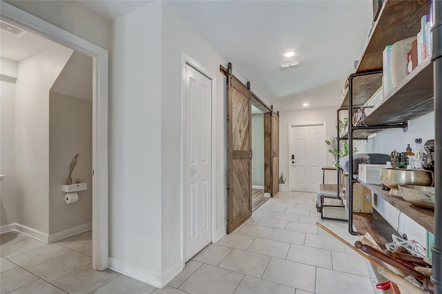 hallway featuring a barn door and light tile patterned flooring