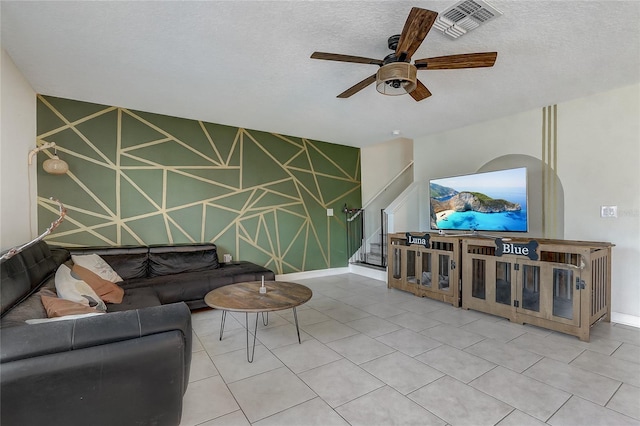 living room with ceiling fan, tile patterned floors, and a textured ceiling