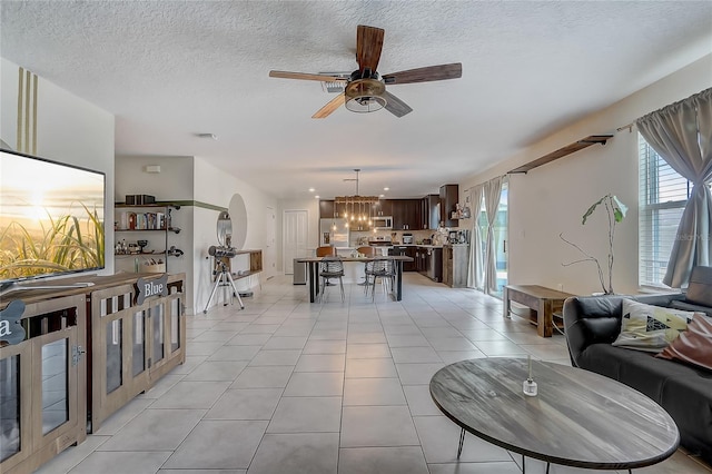 tiled living room with plenty of natural light, ceiling fan with notable chandelier, and a textured ceiling