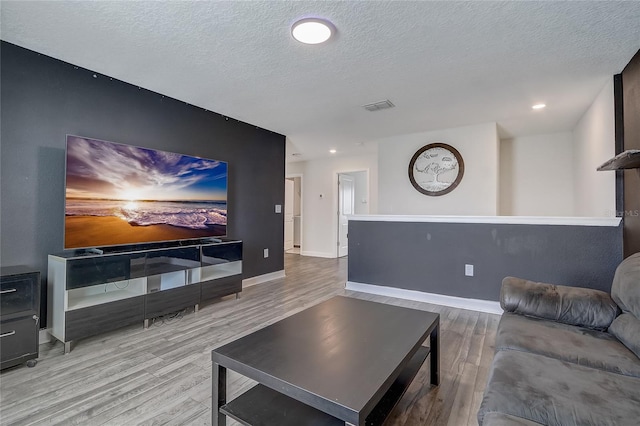 living room with a textured ceiling and light wood-type flooring