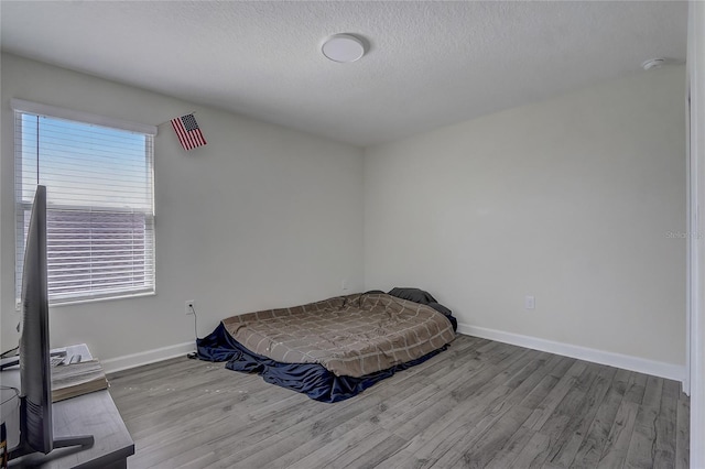 bedroom with light hardwood / wood-style flooring and a textured ceiling