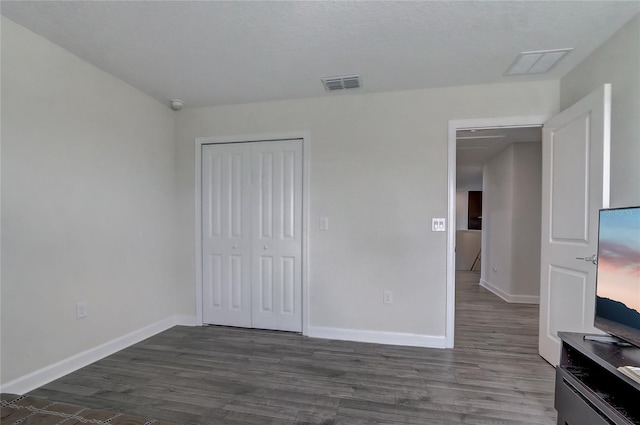 unfurnished bedroom featuring dark hardwood / wood-style flooring and a closet