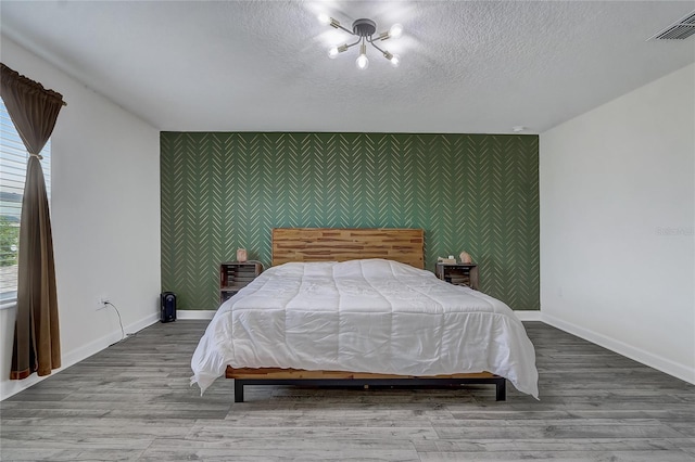 bedroom with a textured ceiling and light hardwood / wood-style floors