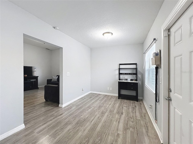 empty room with a textured ceiling and light hardwood / wood-style flooring