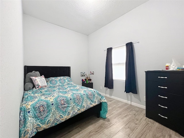 bedroom with a textured ceiling and light wood-type flooring