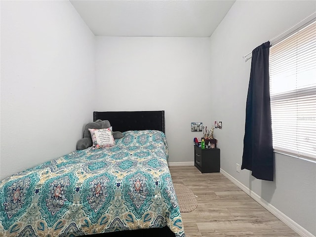 bedroom with multiple windows and light hardwood / wood-style flooring