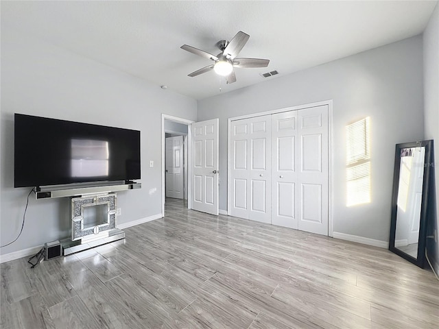 unfurnished bedroom with ceiling fan, a closet, and light wood-type flooring