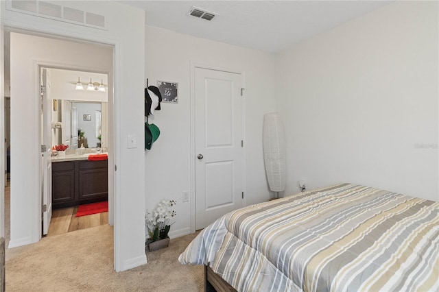 bedroom featuring connected bathroom and light carpet