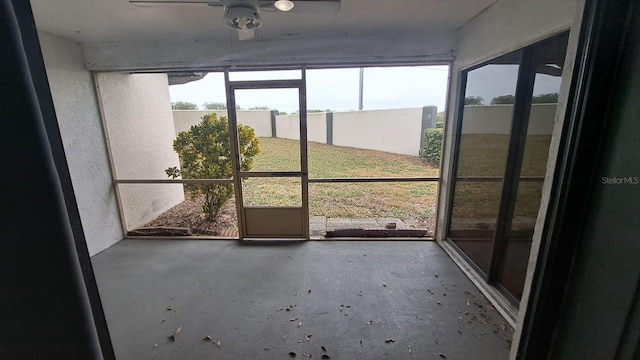 unfurnished sunroom featuring ceiling fan and plenty of natural light