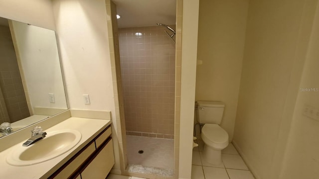 bathroom featuring tile patterned flooring, vanity, tiled shower, and toilet