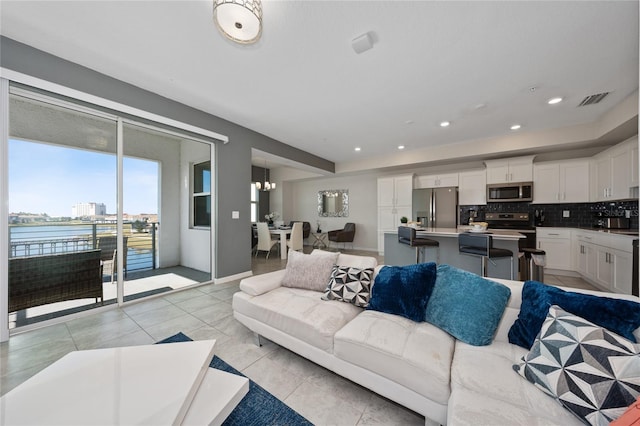 living room with a notable chandelier, light tile patterned floors, and a water view