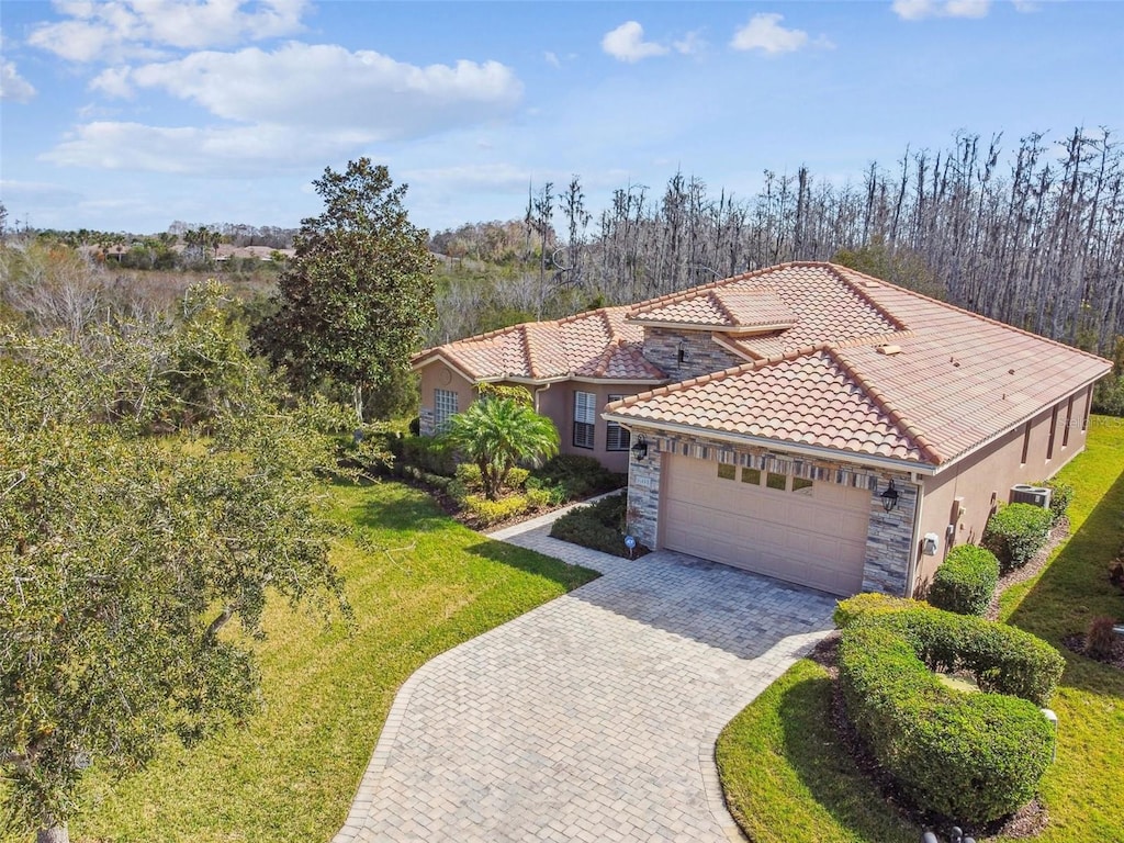 mediterranean / spanish home with cooling unit, a garage, and a front lawn