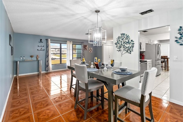 tiled dining room featuring a chandelier and a textured ceiling