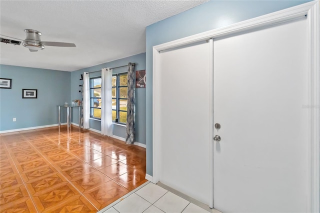 entrance foyer with ceiling fan, tile patterned floors, and a textured ceiling