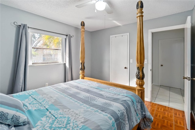 bedroom with ceiling fan, parquet flooring, and a textured ceiling