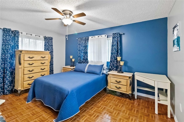 bedroom with dark parquet flooring, ceiling fan, and a textured ceiling