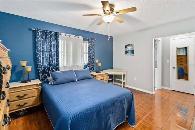 bedroom with ceiling fan, parquet flooring, and a textured ceiling