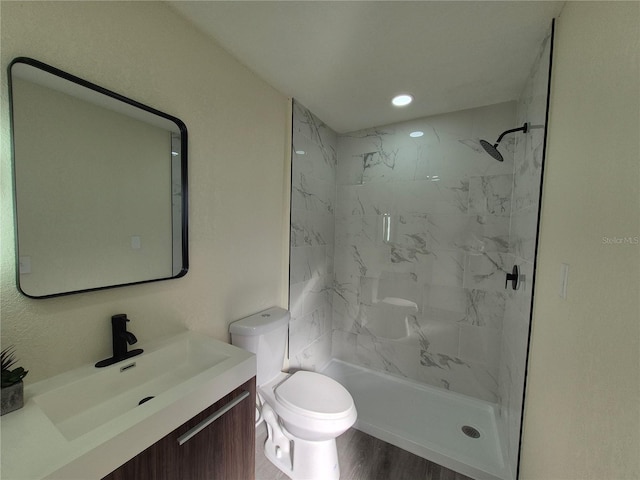 bathroom with vanity, hardwood / wood-style flooring, toilet, and a tile shower