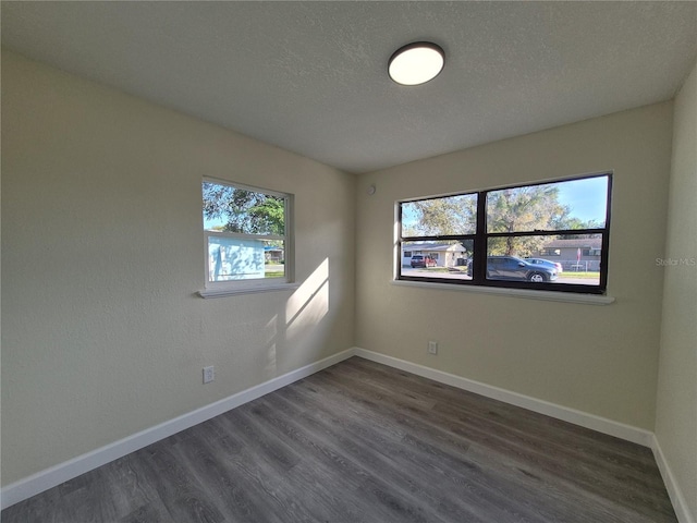 empty room with dark wood-type flooring and a textured ceiling