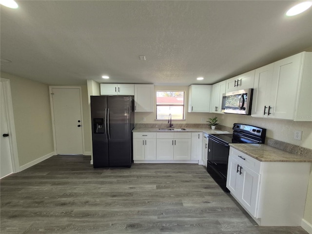 kitchen with sink, light hardwood / wood-style flooring, white cabinets, and black appliances