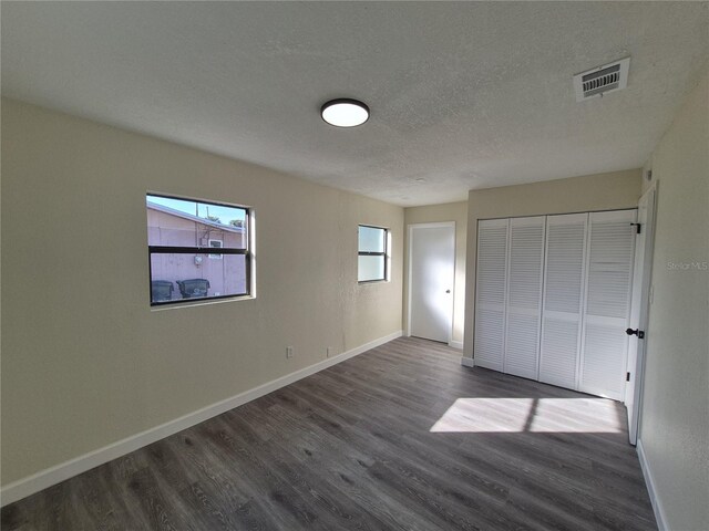 unfurnished bedroom featuring a closet, dark hardwood / wood-style floors, and a textured ceiling