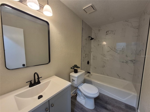 full bathroom featuring toilet, tiled shower / bath, a textured ceiling, vanity, and hardwood / wood-style floors