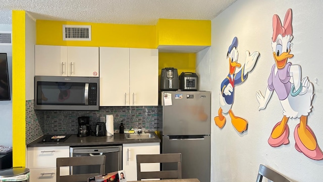 kitchen with sink, a textured ceiling, stainless steel appliances, decorative backsplash, and white cabinets