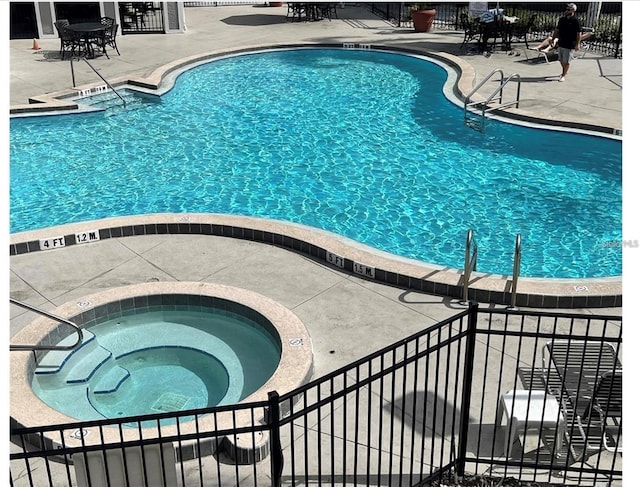 view of swimming pool with a patio area and a hot tub