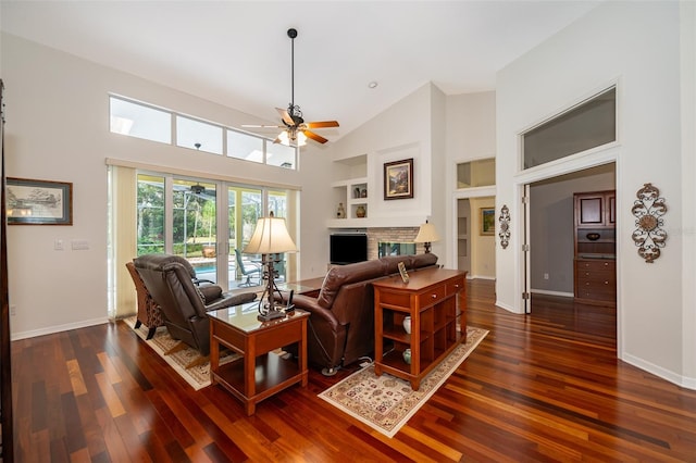 living room featuring dark wood-type flooring, built in shelves, high vaulted ceiling, ceiling fan, and a fireplace