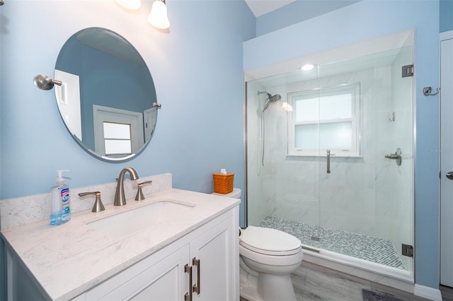 bathroom with vanity, hardwood / wood-style flooring, a shower with door, and toilet