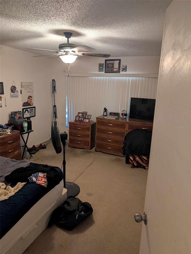 carpeted bedroom with ceiling fan and a textured ceiling