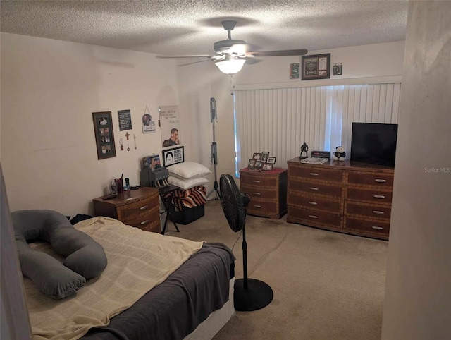 bedroom with ceiling fan, light carpet, and a textured ceiling