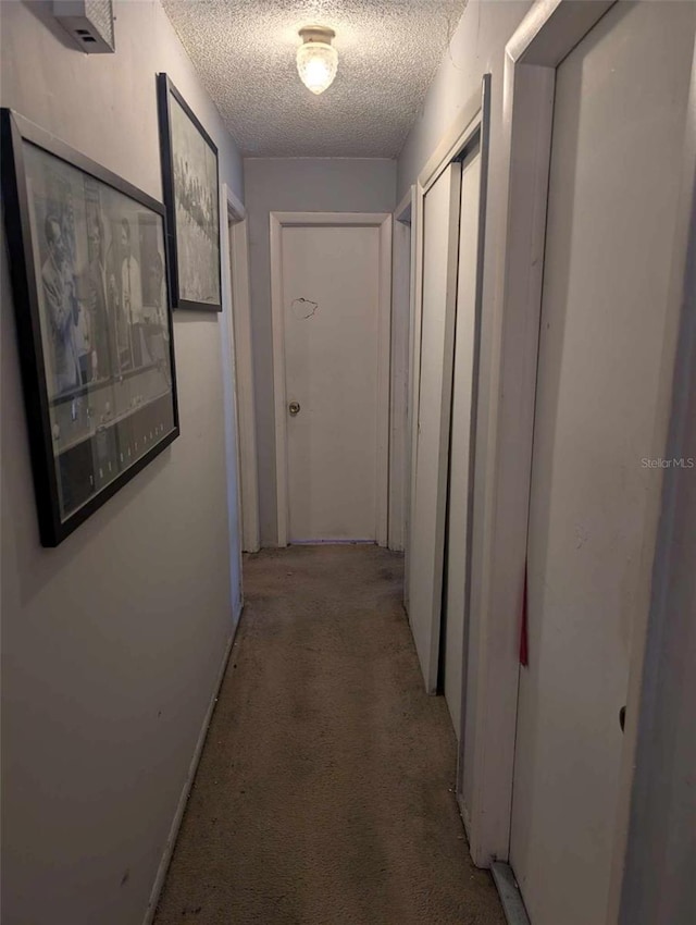 hallway with light carpet and a textured ceiling