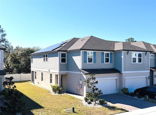 rear view of property featuring a yard, a garage, and solar panels