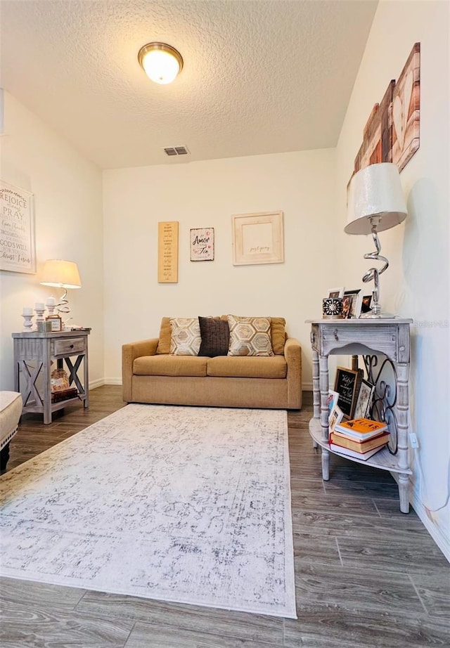 living room featuring dark wood-type flooring and a textured ceiling