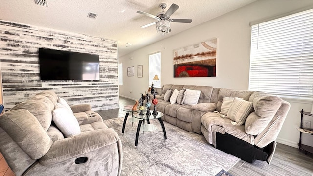 living room featuring ceiling fan, hardwood / wood-style floors, and a textured ceiling