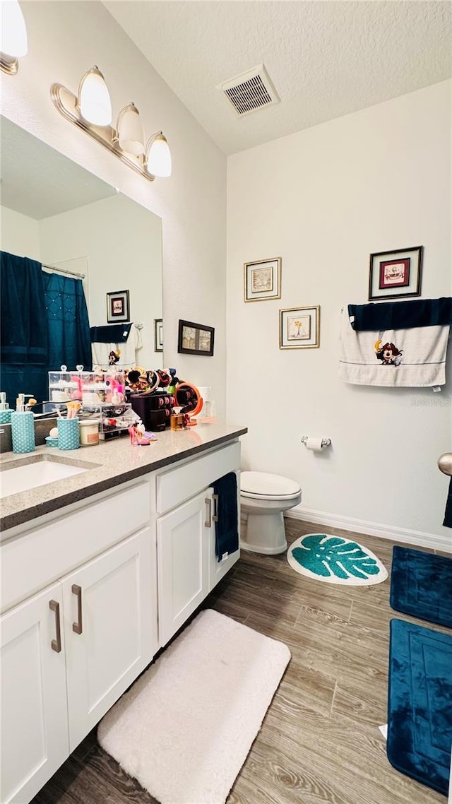 bathroom with vanity, hardwood / wood-style floors, a textured ceiling, and toilet