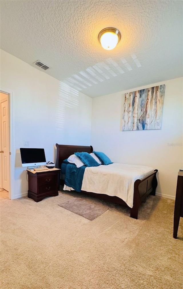 bedroom with light carpet and a textured ceiling