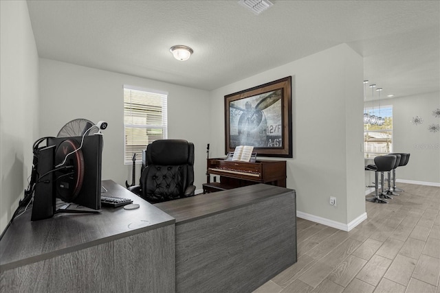 office area featuring a textured ceiling, light hardwood / wood-style flooring, and a wealth of natural light