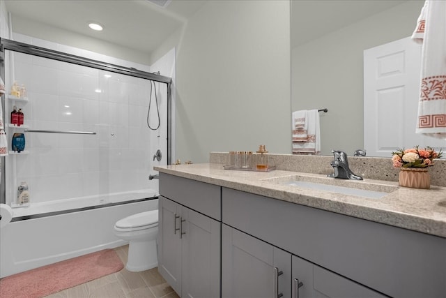 full bathroom featuring vanity, tile patterned flooring, bath / shower combo with glass door, and toilet