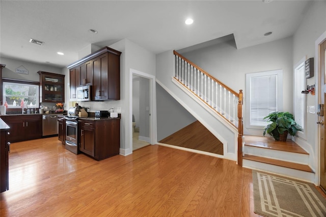 kitchen featuring dark countertops, visible vents, appliances with stainless steel finishes, light wood-style floors, and dark brown cabinetry