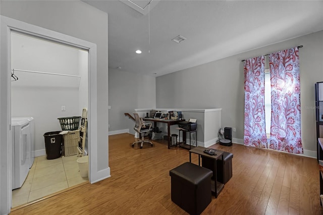 home office featuring attic access, baseboards, wood finished floors, and washing machine and clothes dryer