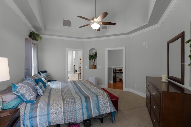 bedroom featuring light carpet, a raised ceiling, visible vents, and a walk in closet