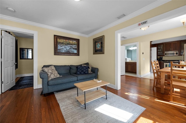 living room featuring baseboards, wood finished floors, visible vents, and crown molding