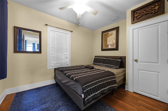 bedroom featuring dark wood-type flooring, visible vents, baseboards, and a ceiling fan