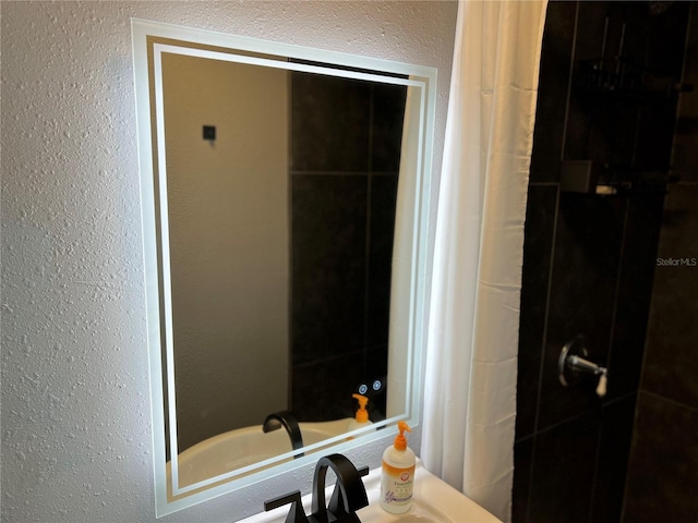 bathroom featuring a tile shower and a textured wall