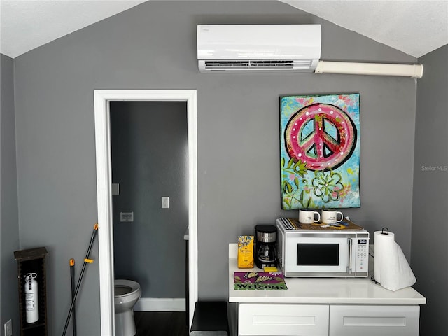 interior space with white microwave, a wall mounted AC, and baseboards