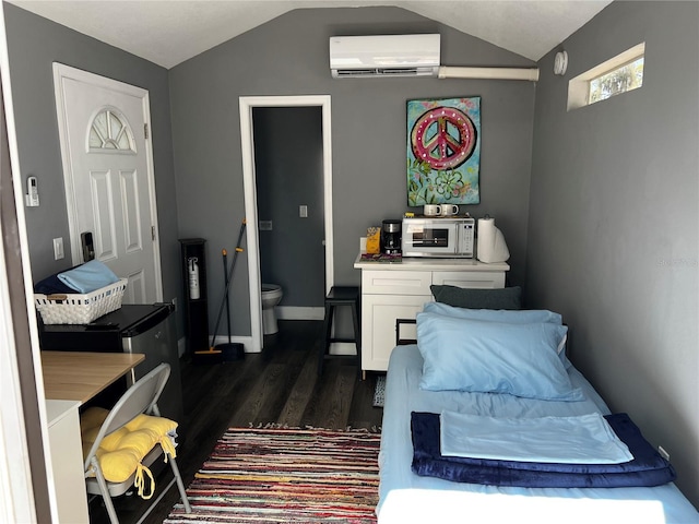 bedroom featuring lofted ceiling, dark wood-style flooring, a wall mounted AC, and baseboards