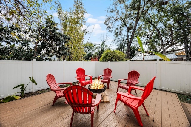 deck with a fenced backyard and a fire pit