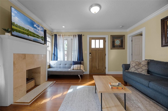 living room with a textured ceiling, ornamental molding, dark wood-type flooring, and a tile fireplace